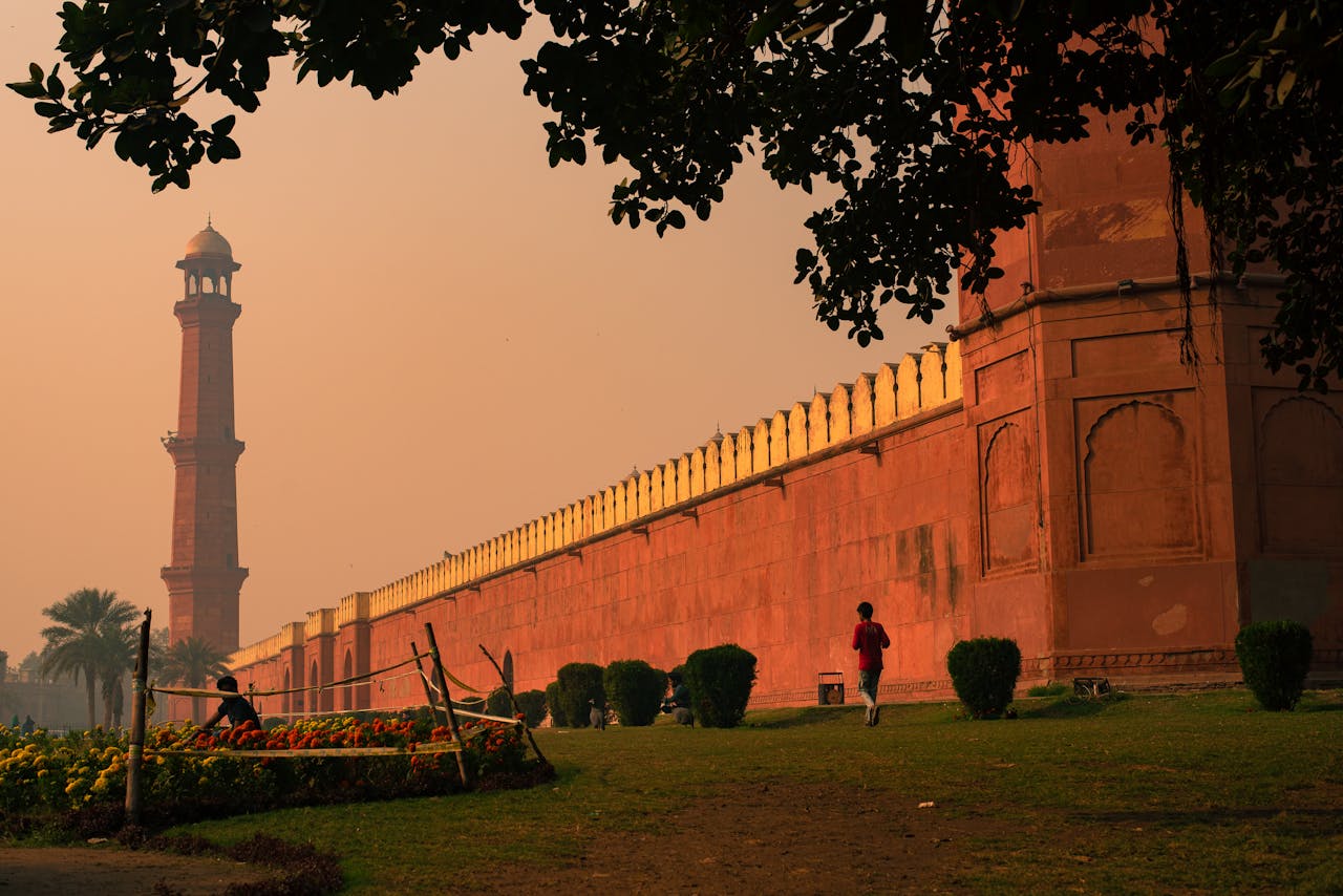 portfolio-img-05 Silhouette of Badshahi Mosque minaret at sunset with trees in the foreground in Lahore, Pakistan.
