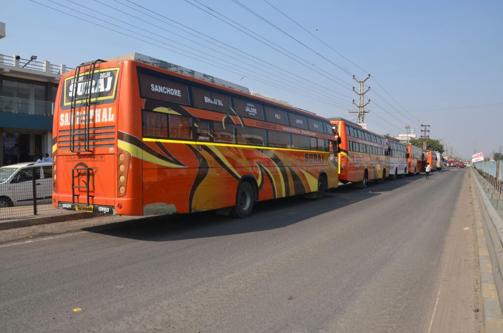A series of vibrant buses parked along a city road in broad daylight.